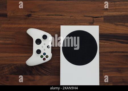 LONDON - OCTOBER 31, 2022: Xbox Series S games console with white gaming controller on wood background Stock Photo