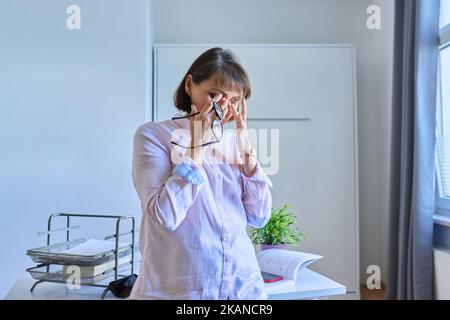 Middle aged woman suffering from headache in home office Stock Photo
