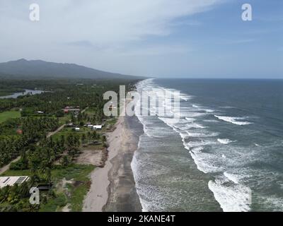 The ocean waves touching the coastline with the green field view, Playa El Espino, Usulutan, El Salvador, aerial Stock Photo