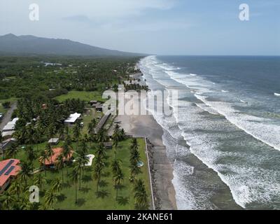 The ocean waves touching the coastline with the green beach view, Playa El Espino, Usulutan, El Salvador, aerial Stock Photo