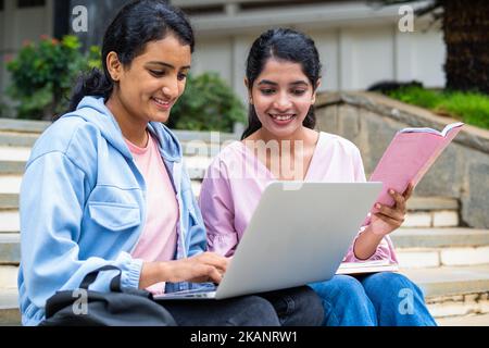 focus on girl with book, Happy College students busy working on laptop while sitting on campus - concept of education, technology and friendship Stock Photo