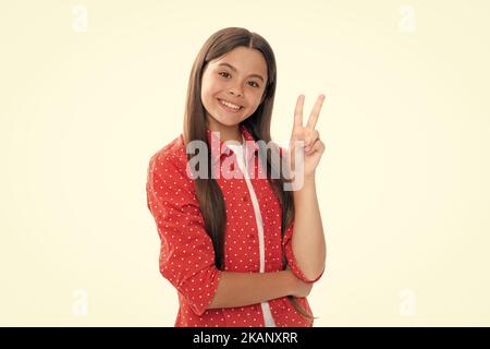 Happy smiling teenage child girl. Portrait of funny cheerful teenager child girl showing v-sign isolated over white background. Stock Photo