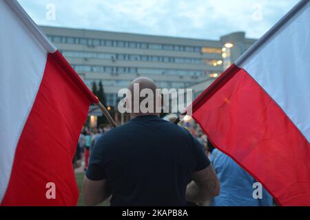 A man holds two Polish national flags during an anti-government candle-lit vigil in front of Krakow's District Court on Monday evening where hundreds gathered for the eighth consecutive night demanding that the Polish President veto the third proposal in relation to judical reform. On Monday, July 24, 2017, in Krakow, Poland. Photo by Artur Widak *** Please Use Credit from Credit Field ***  Stock Photo