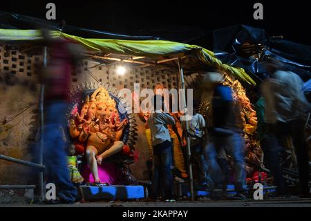 An indian man speaks on phone as others pass near a huge idol of Elephant headed hindu lord Ganesha , ahead of Ganesha Chaturthi festival , in a workshop , in Allahabad on August 24,2017.Ganesh Chaturthi 2017 celebration begin from August 25 till September 5. The festival celebrates the birth and homecoming of Lord Ganesha. (Photo by Ritesh Shukla/NurPhoto) Stock Photo