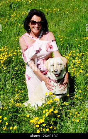 An attractive female hold her pet labrador in summer sunshine - John Gollop Stock Photo