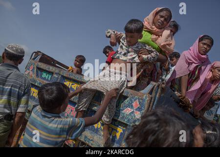 A Rohingya refugee kid is being pulled down from a truck that carried the refuges from the border to Balukhali refugee camps. Cox’s Bazar, Bangladesh. September 16, 2017. (Photo by Turjoy Chowdhury/NurPhoto) Stock Photo