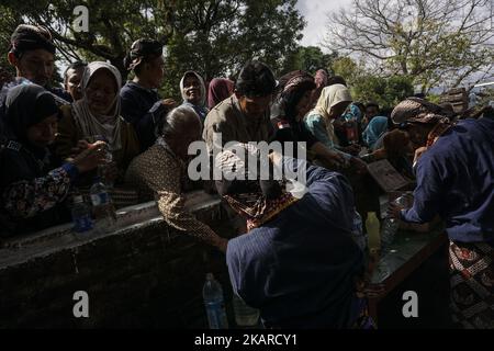 Javanese people follows the ritual of Nguras Enceh ceremony in the complex of the Tomb Kings Mataram at Yogyakarta, Indonesia, on September 22, 2017. Enceh drained a procession drain and fill the water back four enceh (big barrel) which is held every month of Muharram (Islamic calendar) or Suro (Javanese calendar) by the courtiers as known as abdi dalem of the Sultanate of Yogyakarta and Surakarta. Water from big barrel was then grabs by the pilgrims are believed to give a blessing and cure the disease. Nguras Enceh ceremony tradition has a meaning discard the bad things and replace them with  Stock Photo