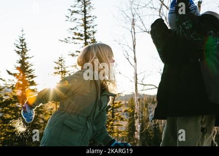 Siblings play in snow in sunshine winter forest Stock Photo