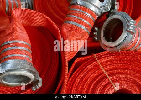 View of many twisted red fire hoses close-up in full screen. New fire extinguishing equipment. Background.. Stock Photo
