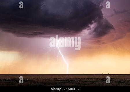 A powerful lightning bolt strikes from a thunderstorm at sunset near Lamar, Colorado Stock Photo