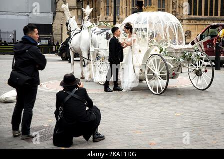 A Chinese couple have pre wedding photographs taken in horse deawn Cinderella carriage outside the Houses of Parliament, London on October 20, 2017. London has become increasingly popular as a location for pre-wedding photography thanks in part to its instantly recognisable landmarks. (Photo by Alberto Pezzali/NurPhoto) Stock Photo
