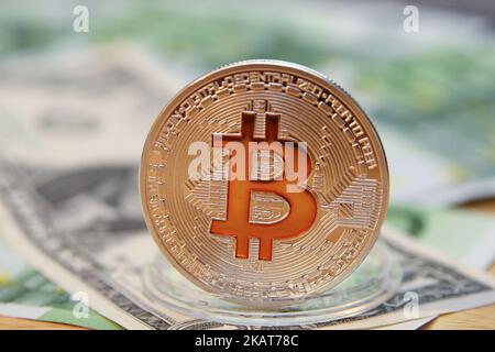 Bitcoin cryptocurrency symbolic coin is seen in front of 100 Euro and 1 US Dollar notes in this photo illustration in Gdansk, Poland on November 1, 2017. The price of bitcoin surpassed the 6,500 and 6,600 USD barrier in one day to hit a new record high on November 1, after U.S.A. based exchange CME said that it would introduce bitcoin futures contracts this quarter, subject to regulatory approval. (Photo by Michal Fludra/NurPhoto) Stock Photo