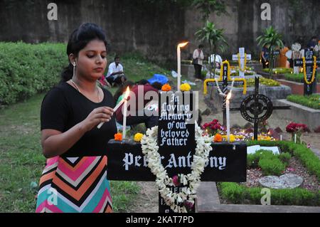 A woman lighting candles on the grave of her relative at a cemetery during the observance of All Souls Day, in Kolkata, India on November 2, 2017. (Photo by Debajyoti Chakraborty/NurPhoto) Stock Photo