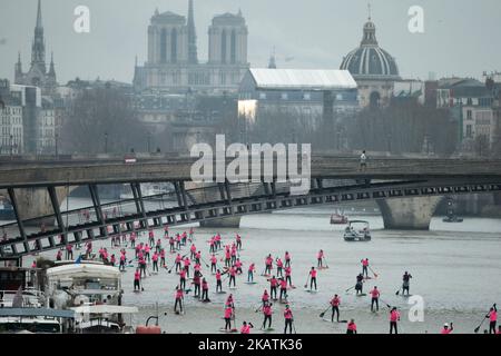 Paddle boarders pass near the Léopold Sedar Senghor bridge as they participate in the morning light in the Nautic SUP Paris crossing on the river Seine on December 3, 2017 in Paris. The Nautic SUP Paris crossing is the biggest Stand Up Paddle race in the world, offering the unique opportunity of paddling down the River Seine past the Eiffel Tower and other iconic landmarks. (Photo by Michel Stoupak/NurPhoto) Stock Photo