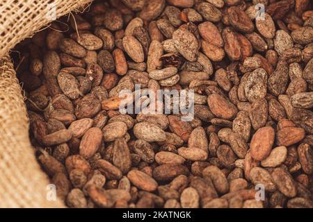 Roasted beans or seeds of Theobroma cacao or cocoa in a jute sack, close up Stock Photo