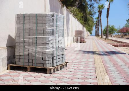 Paving stones on wooden pallet on the street sidewalk. Construction Paving of city streets and adjoining territories. Outdoor tile concrete paving blo Stock Photo