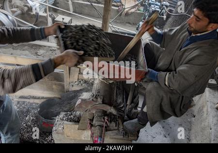 A Kashmiri man grinds water chestnuts to obtain flour at a mill on January 05, 2018 in Kolhom, north of Srinagar, the summer capital of Indian Administered Kashmir, India. Water chestnuts are a major crop for people living near Wular lake , Asia's second largest freshwater lake. Wular, looks more like a flat marshy plain than a large lake in winters, as the water level recedes entire families collect and extract the marble-sized fruit from its spiky casing . The sun-dried chestnuts are later sold in markets, particularly in summer capital city Srinagar, and are consumed raw or roasted and even Stock Photo