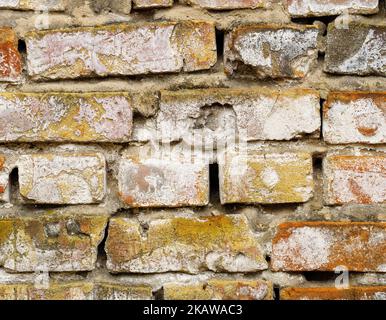 The old brick wall is crumbling and weather-beaten Stock Photo