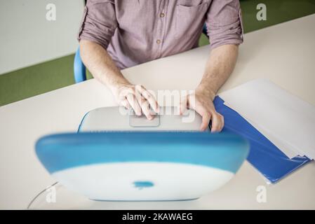 A member of staff shows iBook G3, release date May 2001, at MacPaw's Ukrainian Apple Museum in Kiev, Ukraine on January 26, 2017. Ukrainian developer MacPaw has opened Apple hardware museum at the company’s office in Kiev. The collection has more than 70 original Macintosh models dated from 1981 to 2017. (Photo by Oleksandr Rupeta/NurPhoto) Stock Photo