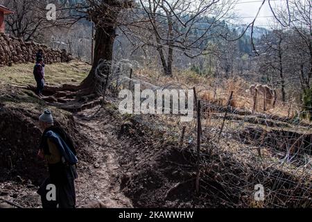 URI, KASHMIR, INDIA - FEBRUARY 27: Kashmiri men walk in front the bunker of Indian army as they walk towards their abandoned home during a fresh skirmish along the border on February 27, 2018 in Uri, 120 Kms (75 miles) north west of Srinagar , the summer capital of Indian administered Kashmir, India. The village with a population of a little over 12,000 has been bearing the brunt of cross-fire between nuclear rivals India and Pakistan. People living along the ceasefire line dividing Kashmir into India and Pakistan-administered portions have continually been at risk due to hostility between the