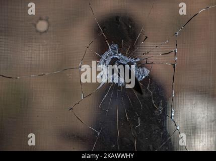 URI, KASHMIR, INDIA - FEBRUARY 27: A man is seen through the bullet pierced glass during a fresh skirmish along the border on February 27, 2018 in Uri, 120 Kms (75 miles) north west of Srinagar , the summer capital of Indian administered Kashmir, India. The village with a population of a little over 12,000 has been bearing the brunt of cross-fire between nuclear rivals India and Pakistan. People living along the ceasefire line dividing Kashmir into India and Pakistan-administered portions have continually been at risk due to hostility between the armies of the two nuclear rivals. Tension betwe Stock Photo