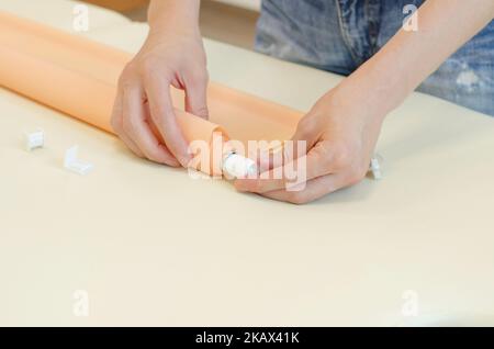 Assembly of roller blinds. Woman's hands assembling roller blinds, close-up Stock Photo