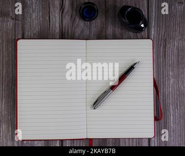 open notebook with pen and inkwell for writing. on wooden background. space to write. top view Stock Photo