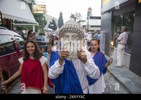 People participate in the 23rd Prometheia festival held in Litochoro, Greece on July 7, 2018. Torchlight procession to celebrate the ancient Greek gods at the foothills of Mount Olympus. The ceremony-festival is called 'Promithia' to honor Prometheus. More than 2000 people attended the torch relay and then to the local open theater for dances and theatrical plays. This year ritual honor Alexander the Great. People arrived in Olympus mountain from all over Greece and Europe. There was even a baby 28 days old in participating with the mother. The ceremonies took place in Dion with a chanting rit Stock Photo