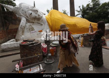 Tourists walk around a reclining Buddha during their visit at Wat Yaichaimongkholl ahead of Asanha Bucha Day in Thailand's Ayutthaya province on July 24, 2018. Asanha Bucha Day, the anniversary of Buddha's first sermon, will be celebrated in Thailand on Friday. (Photo by Chaiwat Subprasom/NurPhoto) Stock Photo