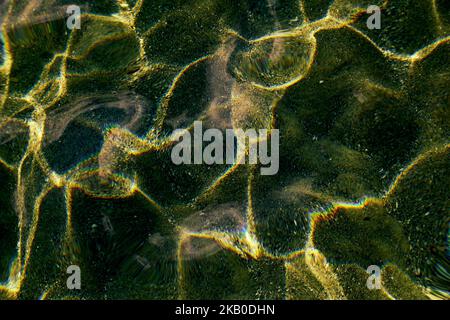 Reflection on the seabed of the refraction of the sun's rays in sea water in shallow water Stock Photo