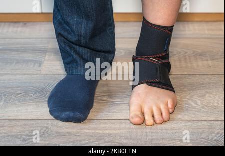 Orthopedic Ankle Brace on foot, wearing elastic ankle bandage wrap, selective focus Stock Photo