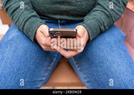 Millennial Caucasian man sitting , holding cellphone, typing online chat message on mobile phone. Stock Photo