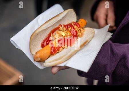 Close up of hotdog in somebody's hand, sausage in a BAP, role, onions ketchup, Stock Photo