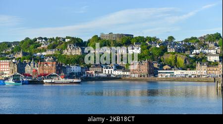 Oban Harbour from the Oban to Mull Ferry with CalMac Ferry and McCaig's Tower  taken early summer evening Stock Photo