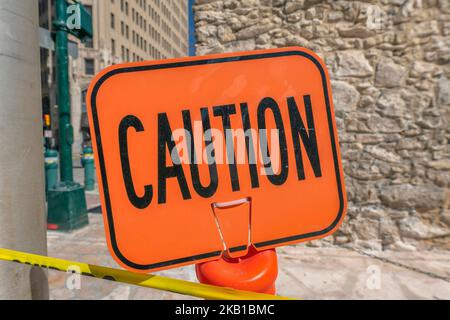 Bright orange Caution sign and yellow tape with stone brick wall background Stock Photo