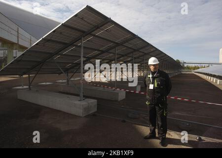 A worker stands by the photovoltaic panels during an official opening ceremony of the new one-megawatt solar power plant ''Solar Chernobyl' next to the New Safe Confinement over the 4th block of the Chernobyl nuclear plant in Ukraine, on 05 October, 2018. Ukraine on Friday launched its first solar plant in the abandoned area around its former Chernobyl power station, the scene of the worst nuclear disaster in the world. The new plant has about 3,800 photovoltaic panels installed across an area of 1.6 hectares just a hundred metres from a giant metal dome sealing the remains the Chernobyl accid Stock Photo