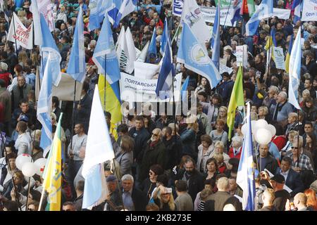 Ukrainians hold placards and flags as they attend a rally organized by the Federation of Trade Unions of Ukraine, in front of the Cabinet of Ministers building, in Kiev, Ukraine, on 17 October, 2018. Thousands Ukrainians took part in a rally dedicated to the International Day for the Eradication of Poverty, demanding an increase in the minimum wage,to low housing and utility tariffs,and ensuring the development of domestic production to create workplaces with proper salary. (Photo by NurPhoto) Stock Photo