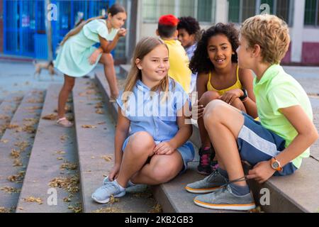 Children talking together while sitting on stairs outdoors Stock Photo
