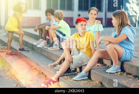 Positive tweenagers friendly blabbing while sitting on steps outdoors Stock Photo