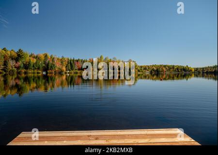 Fall colors trees reflecting on lake Stock Photo