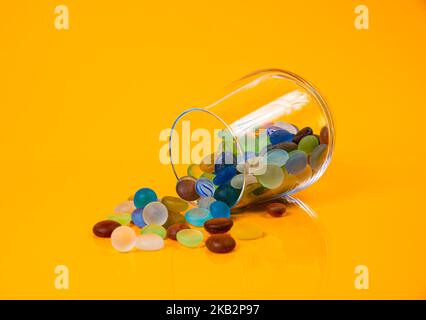 colored stones in glass in jar in bucket on orange background isolated Stock Photo
