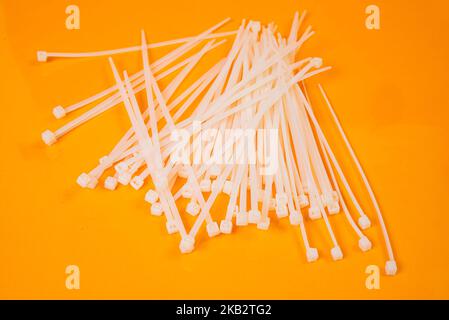 nylon cable ties in glass in jar in bucket on orange background front top view isolated Stock Photo