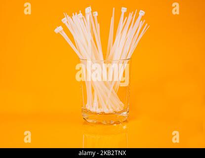nylon cable ties in glass in jar in bucket on orange background front top view isolated Stock Photo