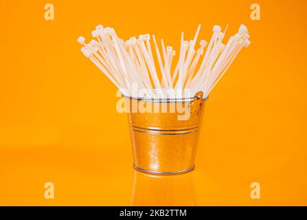 nylon cable ties in glass in jar in bucket on orange background front top view isolated Stock Photo
