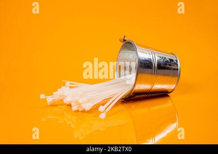 nylon cable ties in glass in jar in bucket on orange background front top view isolated Stock Photo