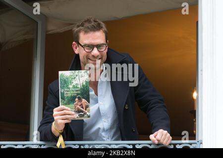 French writer Nicolas Mathieu (C) poses with his book 'Leurs enfants apres eux' on the balcony of Drouant restaurant after winning the Prix Goncourt, France's top literary prize, on November 7, 2018 in Paris. (Photo by Michel Stoupak/NurPhoto) Stock Photo
