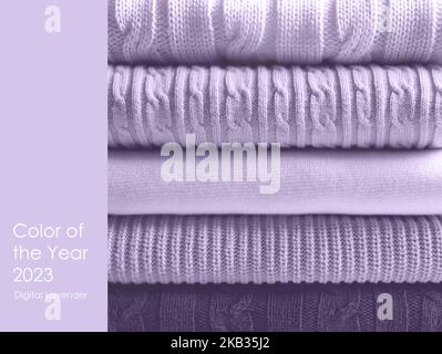 Pile of wool sweaters in trendy colour of the year 2023 digital lavender. Wool cashmere fabric, knitted wool sweaters of pastel colors in stack. Text Color of the year 2023 Digital Lavender Stock Photo