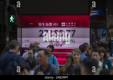 A photo showing Pedestrian walking pass an electronic display board which shows the Heng Seng index in Hong Kong, China. 3 December 2018. The Heng Seng index closed today at 27,182.04 which gain 675.29Â (2.55%) . (Photo by Harry Wai/NurPhoto) Stock Photo
