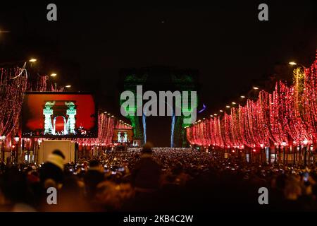 People gather near the illuminated Arc de Triomphe on the Champs-Elysees for New Year's celebrations in the French capital Paris on December 31, 2018. A fireworks display and sound and light show under the theme 'fraternity' is set to go ahead on the Champs-Elysees despite plans for further 'yellow vest' anti-government protests at the famed avenue. (Photo by Sameer Al-Doumy/NurPhoto) Stock Photo