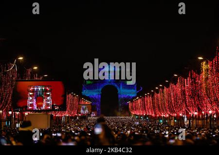 People gather near the illuminated Arc de Triomphe on the Champs-Elysees for New Year's celebrations in the French capital Paris on December 31, 2018. A fireworks display and sound and light show under the theme 'fraternity' is set to go ahead on the Champs-Elysees despite plans for further 'yellow vest' anti-government protests at the famed avenue. (Photo by Sameer Al-Doumy/NurPhoto) Stock Photo